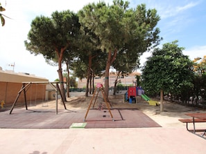 An outdoor playground with swings, a slide, and a climbing structure. - APARTAMENTO LAS TORRES by Interhome (El Campello/Villajoyosa)