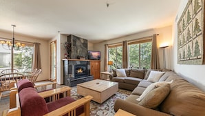 A living room with a fireplace, a sofa, a coffee table, and a TV. - Mountainside at Palisades Tahoe Lodge (Olympic Valley)