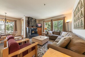 Een woonkamer met een open haard, een bank, een salontafel en een televisie.