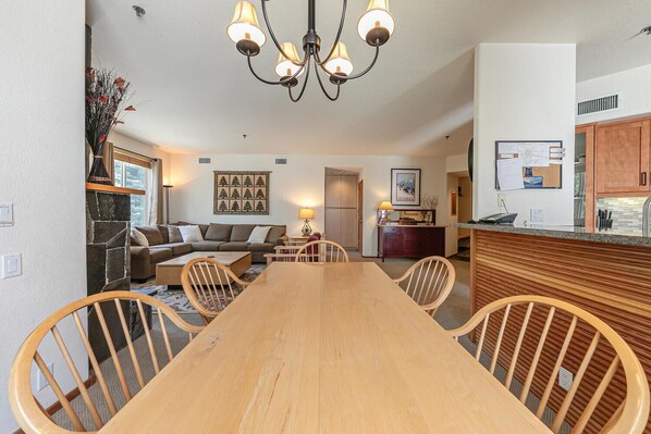 A spacious living room with a wooden dining table, a sofa, and a chandelier.