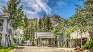 A hotel entrance with a covered driveway, surrounded by trees and a mountain in the background. - Mountainside at Palisades Tahoe Lodge (Olympic Valley)