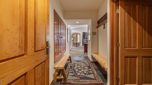 A hallway with wooden doors, a bench, and a patterned rug. - Mountainside at Palisades Tahoe Lodge (Olympic Valley)