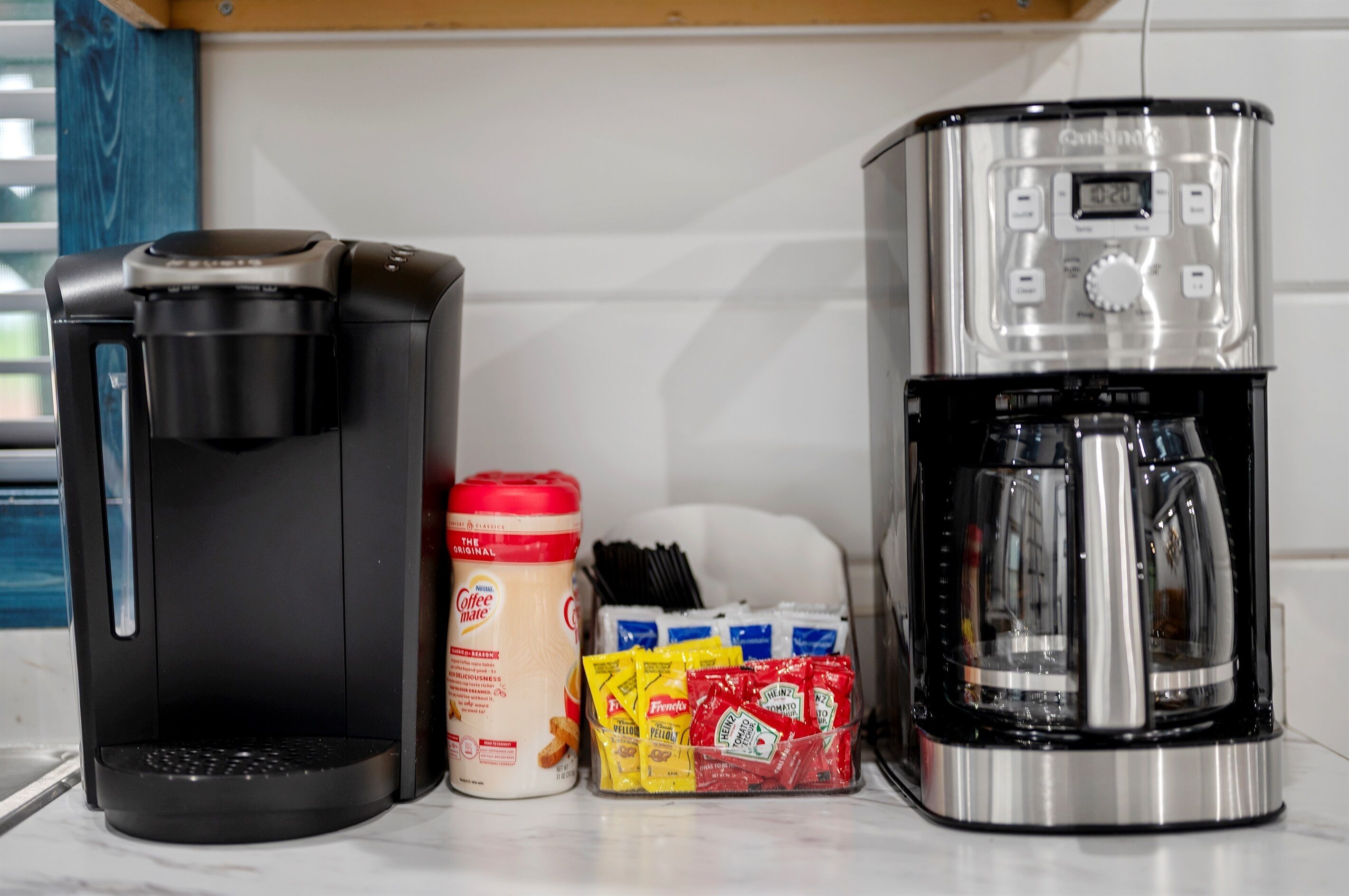 A coffee maker, a coffee pot, and a container of coffee creamer.