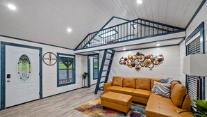 Un salon spacieux avec un grand canapé d’angle, un tapis coloré et un élément décoratif mural.