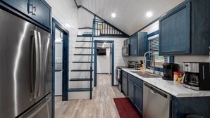 Une cuisine moderne dotée d’appareils électroménagers en acier inoxydable, d’un tapis rouge et d’un escalier menant à un niveau supérieur.
