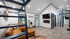 Un salon moderne avec un canapé, un téléviseur et une cheminée.