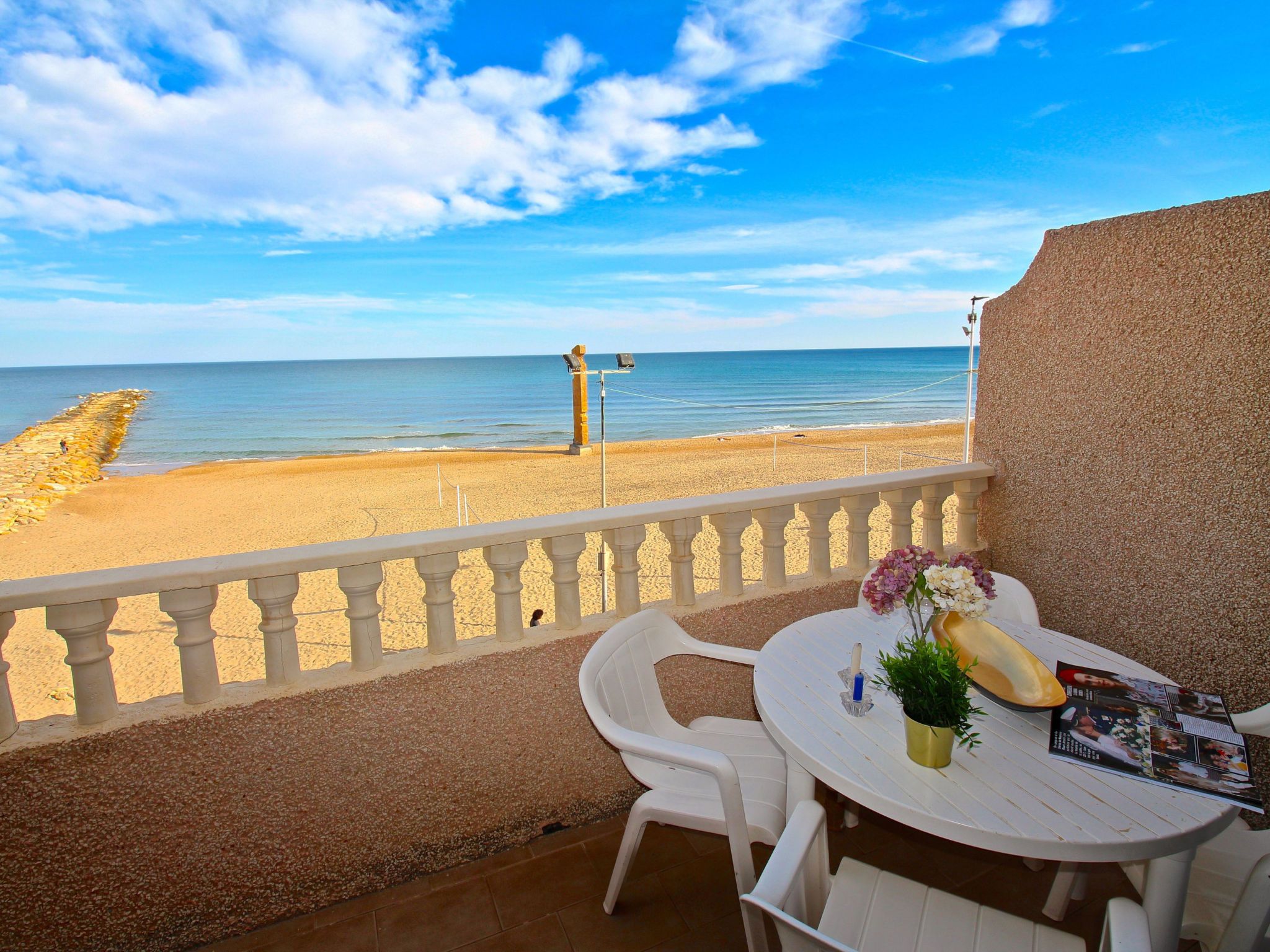 Un balcon avec une table, des chaises et une vue sur la plage et la mer.
