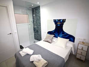 A modern hotel room with a large bed, a glass shower enclosure, and a decorative headboard. - APART. GRANDE Y LUMINOSO EN EL CENTRO DE ALICANTE by Interhome (Alicante)