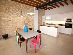 A modern kitchen with white cabinets, a built-in oven, and a dining area with a wooden table and chairs. - APART. GRANDE Y LUMINOSO EN EL CENTRO DE ALICANTE by Interhome (Alicante)