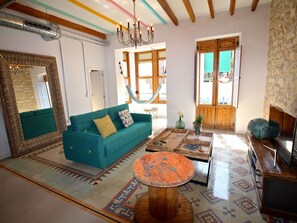 Una sala de estar con un sofá color turquesa, una mesa de centro de madera y una hamaca.
