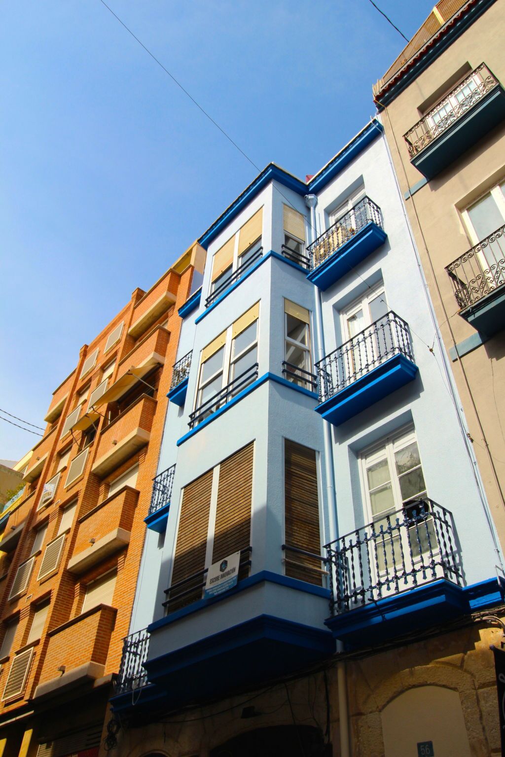 Un edificio de varios pisos con balcones y un cielo despejado.