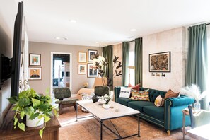 A living room with a sofa, a coffee table, a chair, and a potted plant. - StayAtlas Retreat w/ Pool, Gym, Sauna, Games, BBQ (St. Louis)