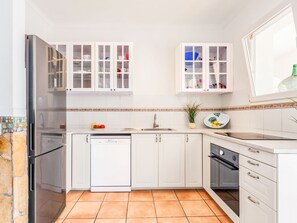 A modern kitchen with white cabinetry, a stainless steel refrigerator, and a dishwasher. - Villa Can Flores by Interhome (Santanyí)