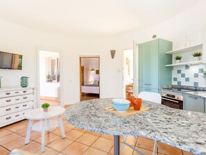 Eine moderne Küche mit einer Granitabdeckung, einem Essbereich mit einem runden Tisch und Blick in ein Schlafzimmer.