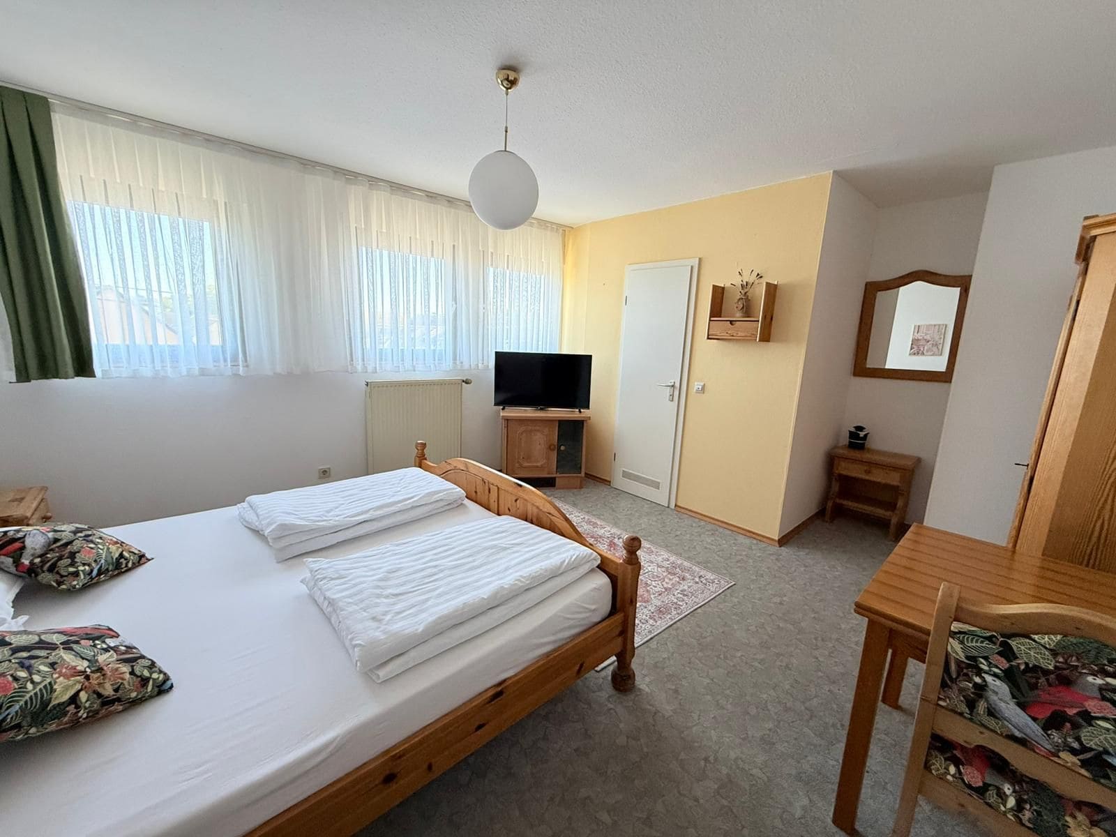 A bedroom with a bed, a television, a desk, and a chair.