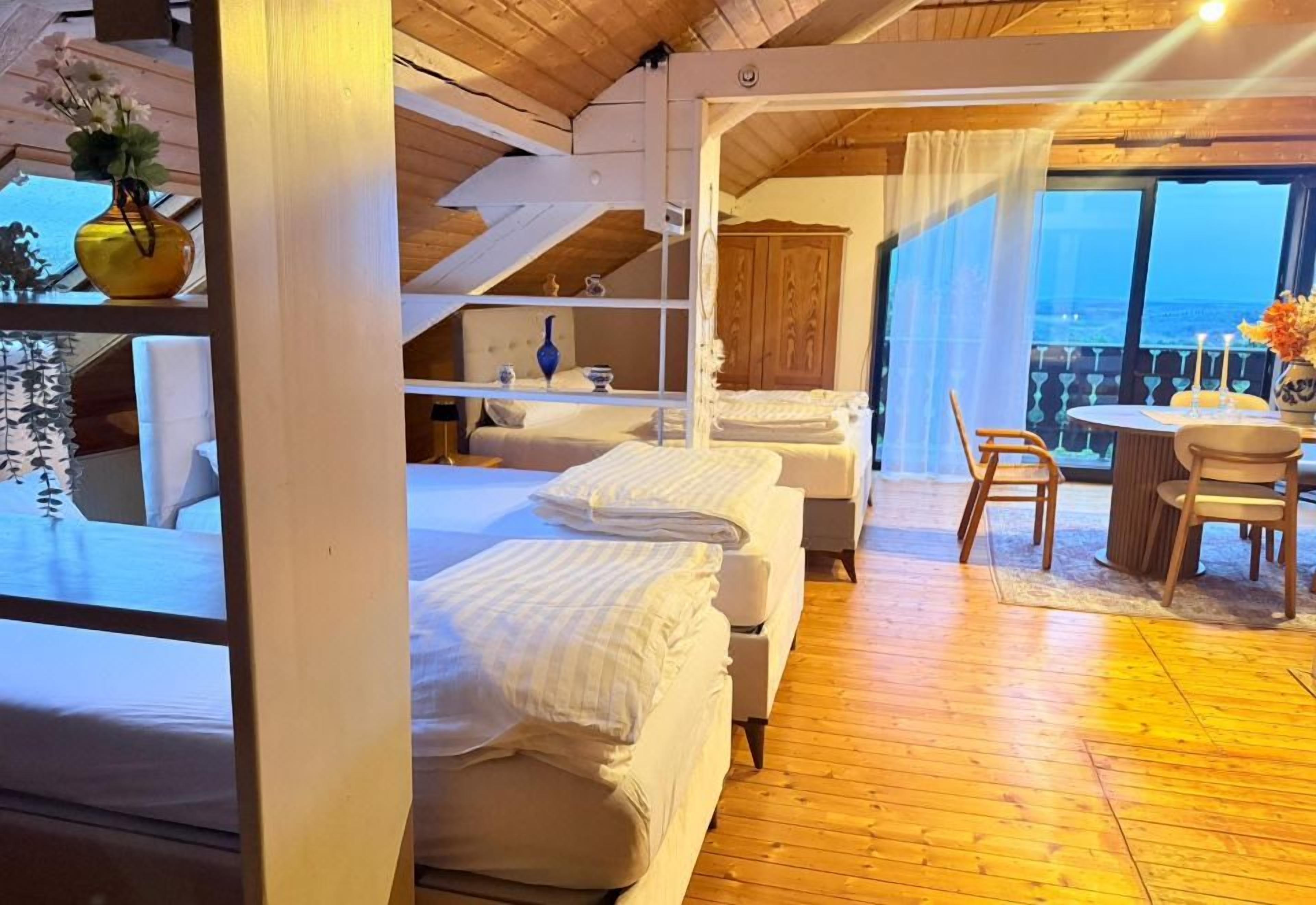 A hotel room with a balcony, wooden flooring, and a bed with white bedding.
