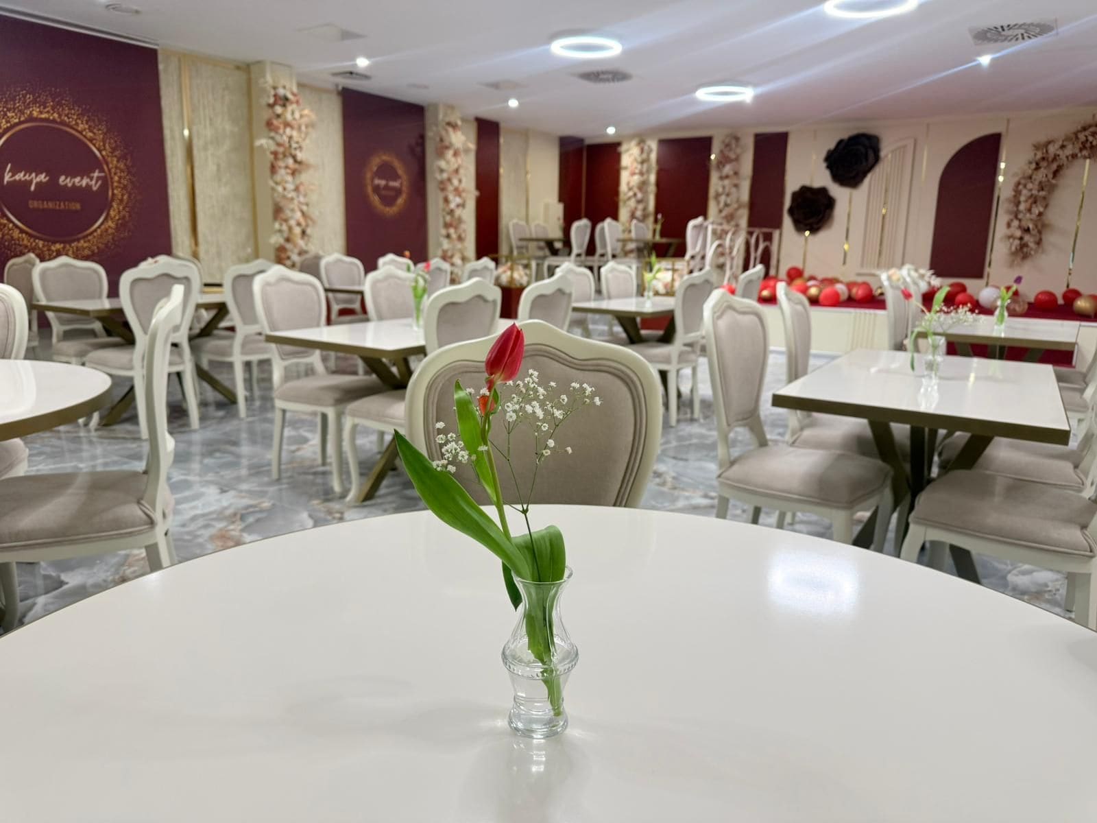 A dining area with round tables, chairs, and floral decorations.