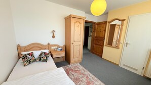 A bedroom with a bed, a nightstand, a wardrobe, a mirror, and a hanging light fixture. - Dreischläger Hof (Neustadt)