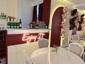 A bar area with a neon sign, a variety of bottles, and a dining area with a table and chairs. - Dreischläger Hof (Neustadt)