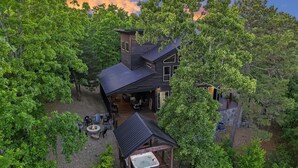 Une cabane moderne à deux étages, dotée d’un bain à remous et entourée d’une forêt dense.