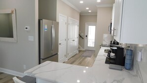 Una cocina moderna con armarios blancos, encimera de mármol y refrigerador de acero inoxidable.