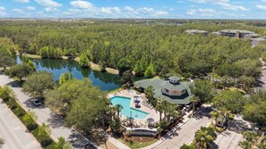 Ein Resort mit Schwimmbad, Laube und Blick auf einen von Bäumen umgebenen See.
