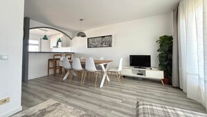 A modern living room with a dining area, a flat-screen TV, and a large plant. - V002 - Cargols de Mar 2 (Empuriabrava)