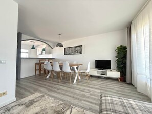 Un saló modern amb zona de menjador, televisió de pantalla plana i una planta gran.