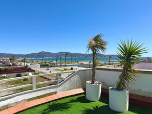 Terrassa al terrat amb gespa artificial, dues plantes en testos i vista al mar i a les muntanyes.