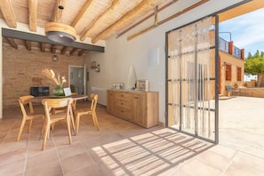 A dining area with a wooden table and chairs, a kitchen with wooden cabinets, and a sliding glass door leading to an outdoor patio. - V038 - Els Masovers (Castelló d'Empúries)
