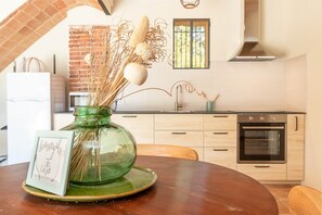 A kitchen with a brick wall, a window, a stove, and a sink. - V038 - Els Masovers (Castelló d'Empúries)