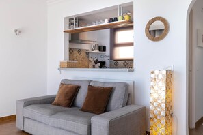 A modern living room with a grey sofa, a coffee station, and a decorative mirror. - V036 - Joan Vinyoli 2 (Roses)