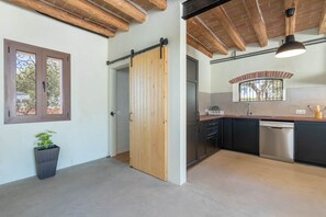 Eine moderne Küche mit einer schiebbaren Holztür, einem integrierten Geschirrspüler und einem Fenster mit schmiedeeisernen Gitterstäben.