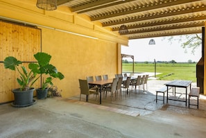Eine Außenpatio mit Esstisch und Stühlen, Blumentöpfen und Blick auf die Landschaft.