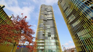 A modern high-rise building with a glass facade, surrounded by a park with trees and a playground. - Apartment  by Interhome (Lucerne)