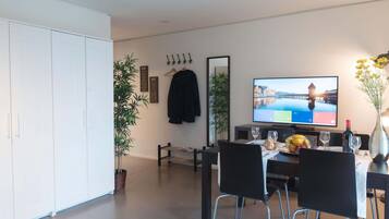 A modern dining area with a TV, chairs, a table, and a plant.