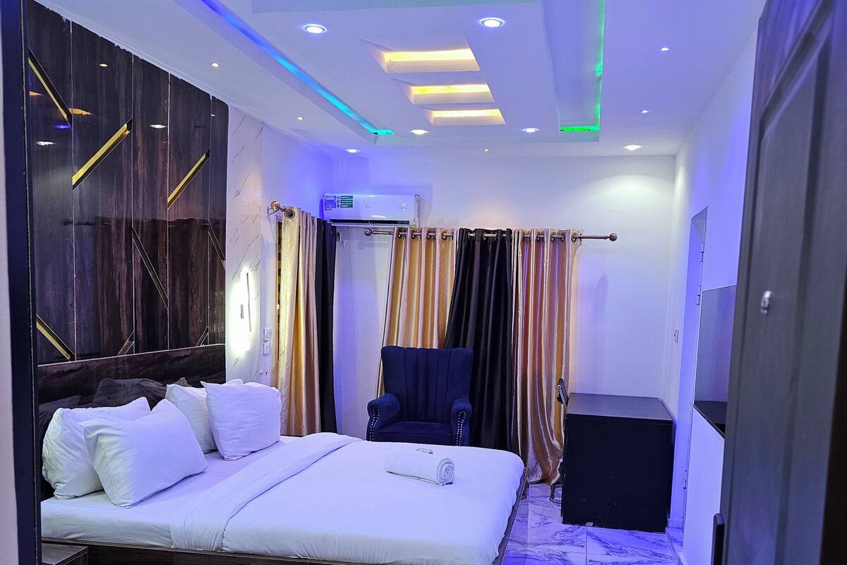 Une chambre d’hôtel moderne  équipée d’un grand lit, d’une chaise, d’un bureau et d’un appareil de climatisation.