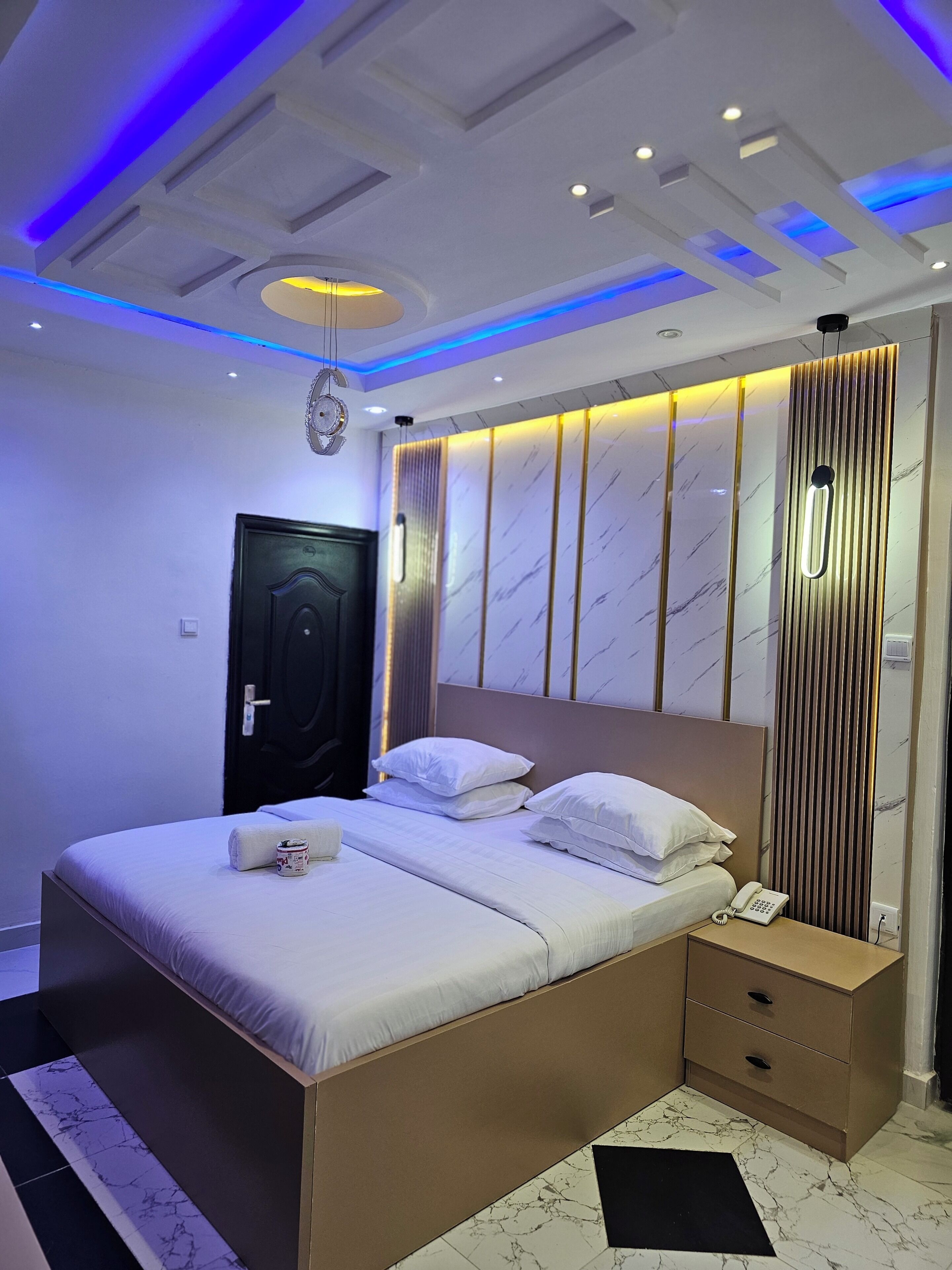 A modern bedroom with a bed, bedside table, and a wall-mounted phone.