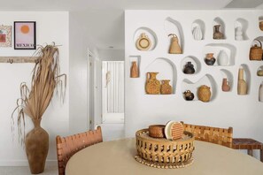 A dining area with a round table, wicker baskets, and a variety of pottery displayed on the wall. - La Casita l Mexican-Inspired Villa with Pool (Warana)