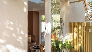 Une terrasse extérieure moderne, agrémentée de plantes en pot, dotée d’un sol à carreaux et d’une porte vitrée donnant sur un espace intérieur.