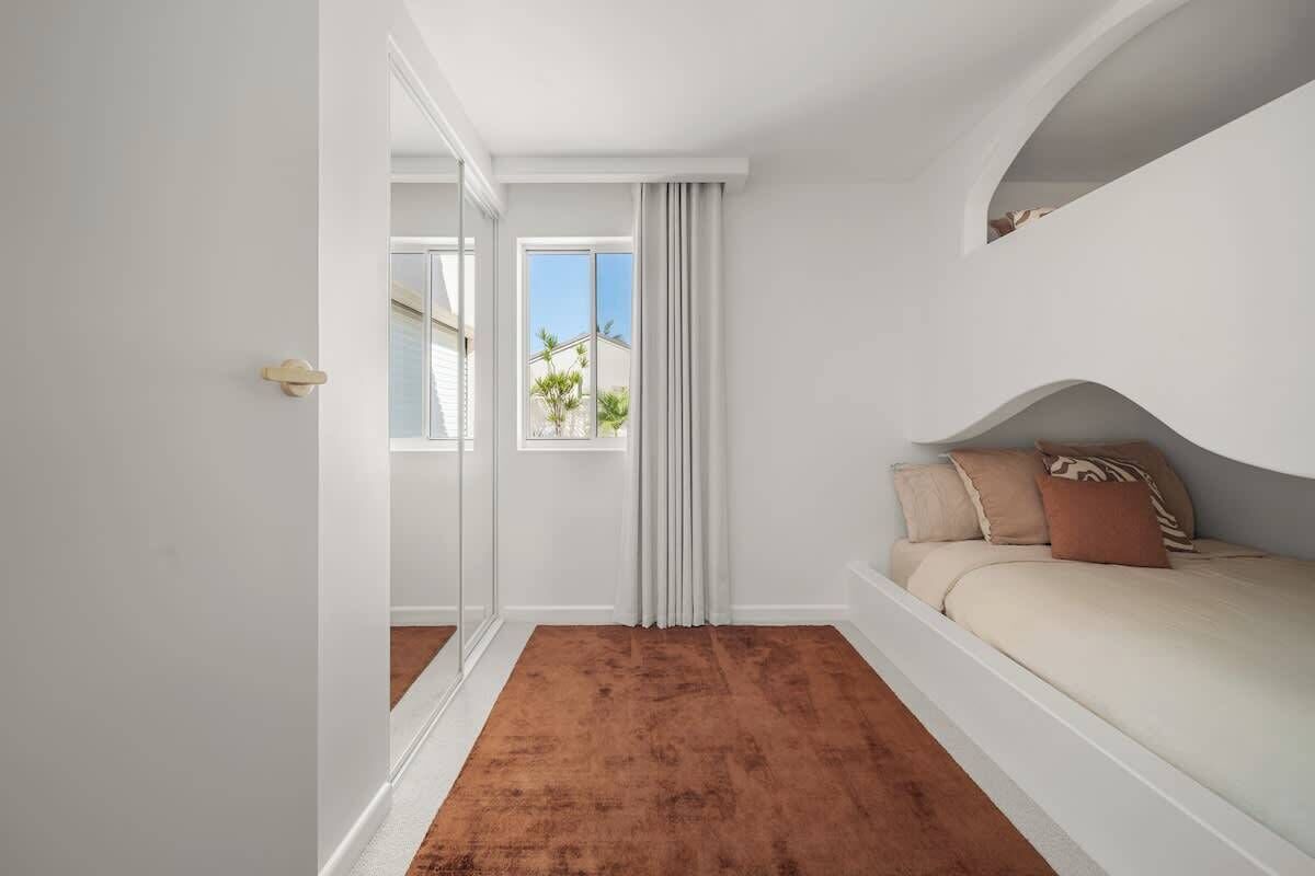 A bedroom with a bed, a window, and a door.