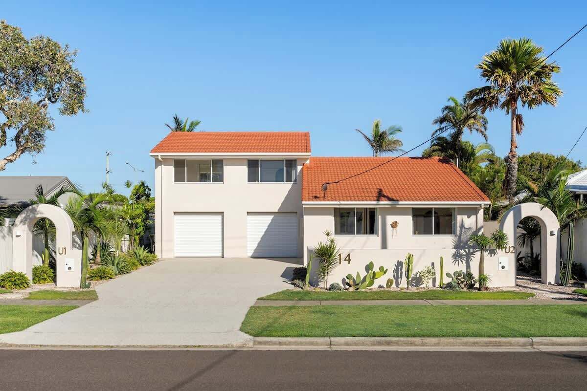 A two-story house with a red-tiled roof, white exterior walls, and a garage.