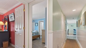 Un couloir avec un lit, une commode et une porte donnant sur une autre pièce.