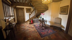 Eine Treppe mit Holzwändern, einem gemusterten Teppich, einem Stuhl und einem Tisch mit Blumen in einer Vase.