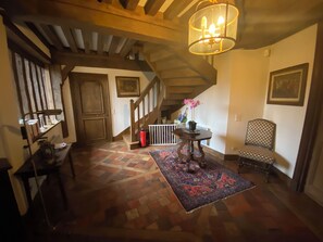 A staircase with wooden railings, a patterned rug, a chair, and a table with a vase of flowers. - Large Norman family home 5km from Deauville (Touques)