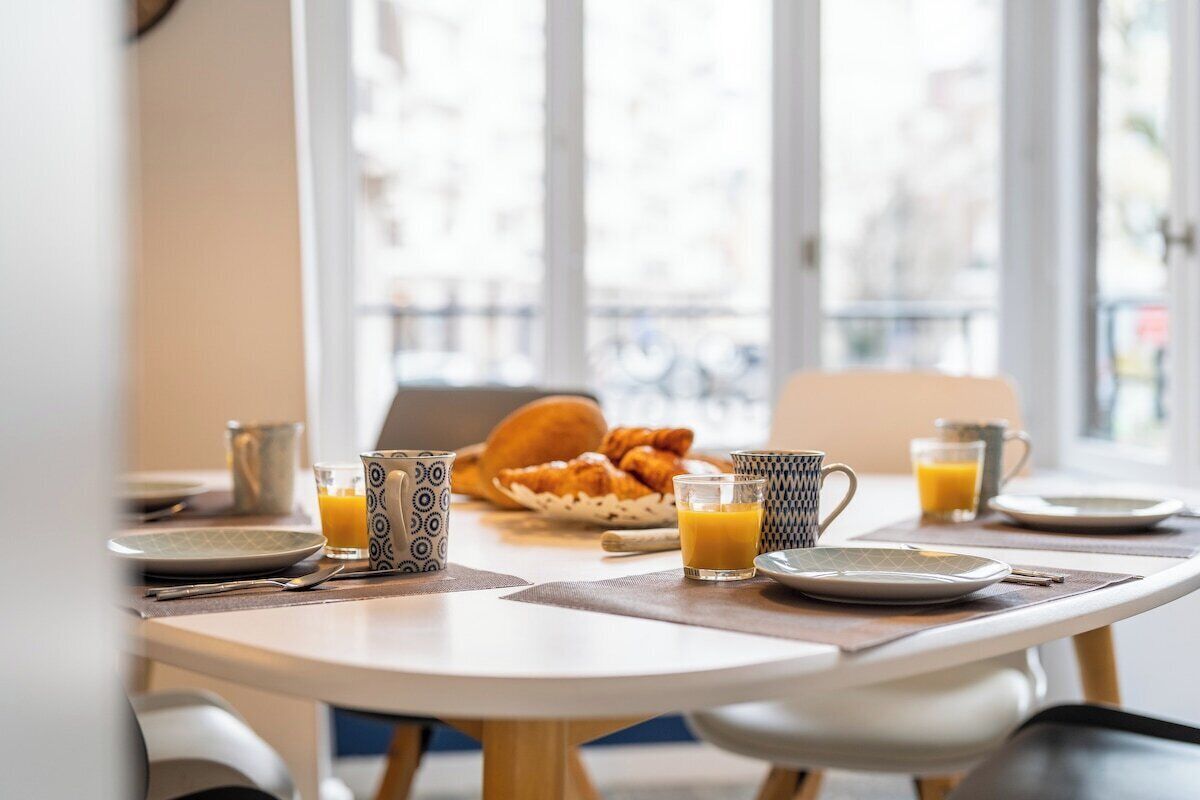 Een ontbijttafel met croissants, sinaasappelsap en koffiekopjes.
