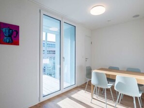 Ein modernes Zimmer mit einer Schiebetür, einem Holztisch mit vier Stühlen und einem Bild an der Wand.