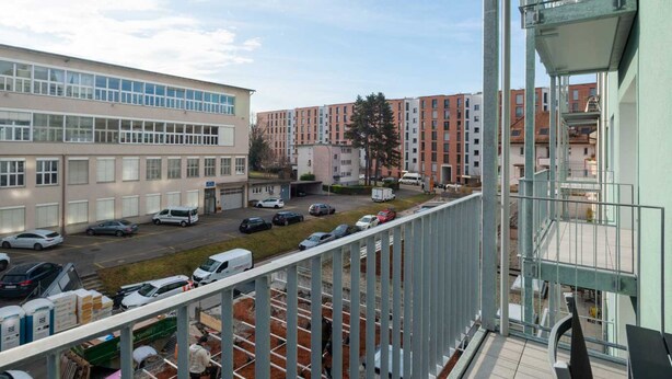En balkong med utsikt över en parkeringsplats och byggnader.