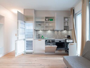 A compact kitchen with built-in appliances, a dishwasher, and a dining area with a sofa. - ZH Red 3 - Letzigrund HITrental Apartment by Interhome (Zurich)