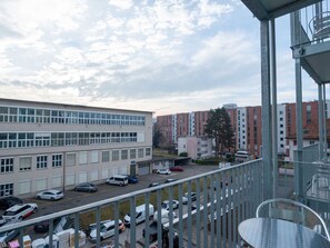 Vista de um estacionamento com vários carros, um edifício de fachada plana e céu claro.